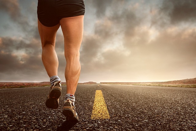 feet running down the middle of a deserted road in sneakers and shorts, clouds in the background