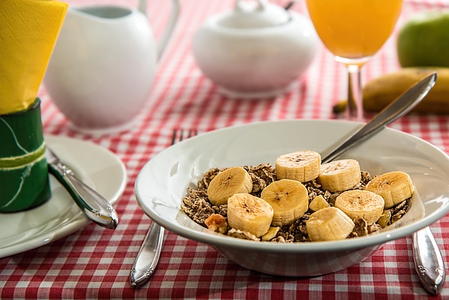 bowl of cereal with bananas on table, ready for eating